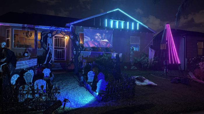 The house lit up for Halloween, with the projector on the front window